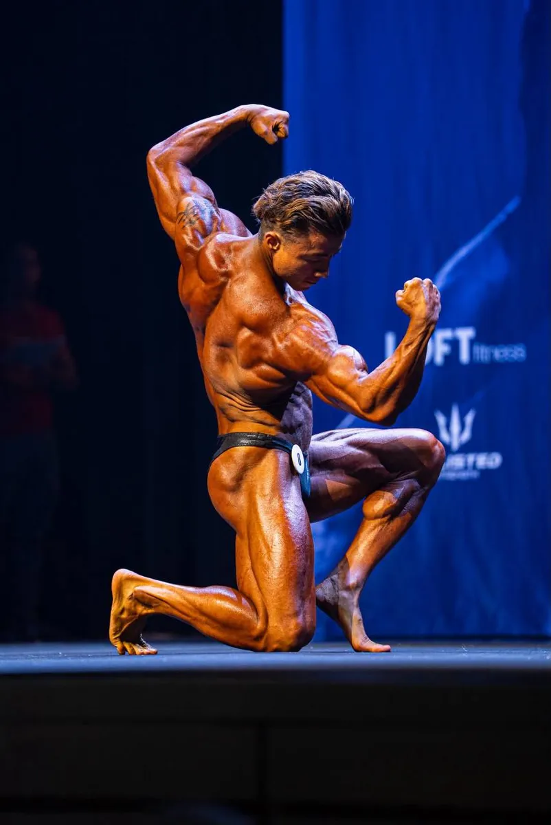Alex Lu i knælende posering under classic physique konkurrence