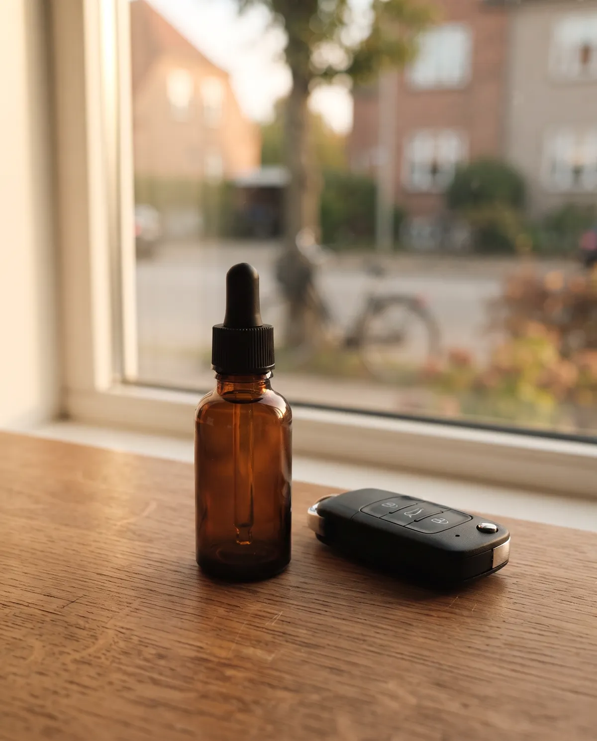 CBD-olie flaske ved siden af en bilnøgle i en vindueskarm